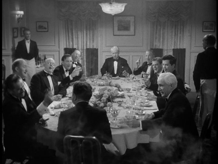 A group of men in tuxedos sit around a table smoking cigars and drinking champagne